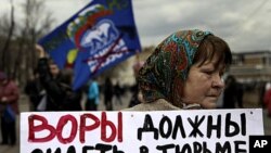 A member of the opposition holds a banner at a protest near the Kremlin, April 16, 2011. The banner reads, "Thieves should go to jail" and displays images of Prime Minister Vladimir Putin.