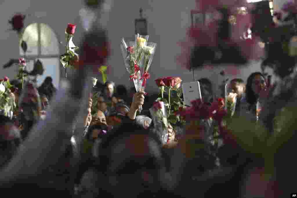 People hold up flowers during a Mass in honor of Our Lady of the Rosary during the annual Afro-Christian Congada celebration in Catalao, Goias state, Brazil, Oct. 8, 2016. After Mass people place their flowers at the statue of the virgin, who represents t
