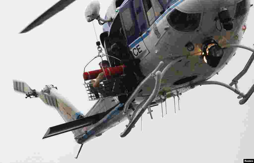 A police helicopter lifts what appears to be a shooting victim up as it hovers over a rooftop on the Washington Navy Yard, Sept. 16, 2013.