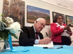 FILE - Former independent counsel Kenneth Starr signs a copy of his recent book "Contempt: A Memoir of the Clinton Investigation" at the University of New Mexico School of Law in Albuquerque, New Mexico, Jan. 23, 2019.