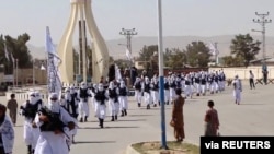 FILE - Taliban fighters march in uniforms on the street in Qalat, Zabul Province, Afghanistan, in this still image taken from social media video uploaded August 19, 2021.