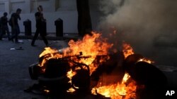 Opponents of ousted President Mohamed Morsi pass by burning vehicles during clashes with Morsi supporters, in Cairo, Egypt, Monday, July 22.