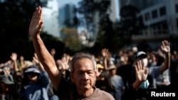 Orang-orang mengangkat tangan ketika mereka bernyanyi dan mendengarkan lagu protes "Glory to Hong Kong" selama protes anti-pemerintah di distrik Tengah Hong Kong, 30 November 2019. (Foto: Reuters/Thomas Peter)