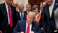 President Donald Trump signs the Waters of the United States (WOTUS) executive order, Feb. 28, 2017, in the Roosevelt Room in the White House in Washington. 