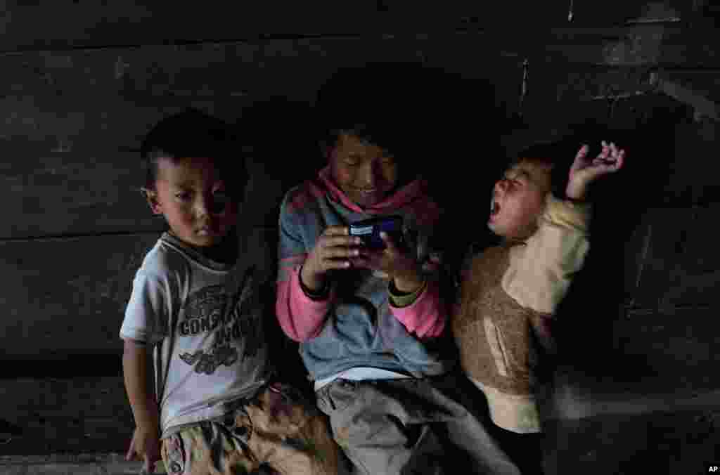 Tangkhul Naga children watch a video on a mobile phone inside their kitchen in Shangshak village, in the northeastern Indian state of Manipur.