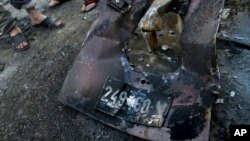 Palestinians inspect abandoned parts with the registration plate of an Israeli army vehicle that was burned during an Israeli army raid in the West Bank refugee camp of Qalandia, at the outskirts of Ramallah, March 1, 2016.