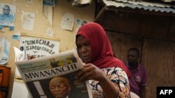 Une femme lit un journal annonçant le décès du président tanzanien John Magufuli à Dar es Salaam, le 18 mars 2021.
