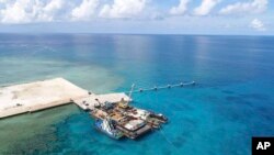 Kapal-kapal yang membawa bahan konstruksi berlabuh di pantai yang baru dibangun di pulau Pag-asa yang diklaim Filipina, juga dikenal sebagai Thitu, di wilayah sengketa Laut China Selatan. (Courtesy: Departemen Pertahanan Nasional Filipina/PAS)