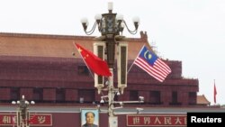 Bendera Malaysia berkibar di sebelah bendera China (kiri) di Lapangan Tiananmen, saat kunjungan Perdana Menteri Mahathir Mohammad di Beijing, China, 19 Agustus 2018. (Foto: Stringer/Reuters)