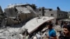 Orang-orang memeriksa puing-puing bangunan tempat tinggal yang hancur akibat serangan udara Israel, di Kota Gaza, 12 Mei 2021. (Foto: AP)