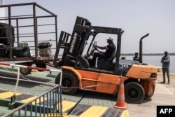 FILE—A dock worker unloads luggage and commerce from the ferry that travels between Dakar and Ziguinchor docks in Ziguinchor on April 10, 2024.