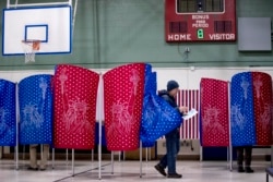 A man walks out of a voting booth during the New Hampshire Primary at Parker-Varney Elementary School, Tuesday, Feb. 11, 2020, in Manchester, N.H. (AP Photo/Andrew Harnik)