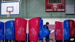 A man walks out of a voting booth during the New Hampshire Primary at Parker-Varney Elementary School, Feb. 11, 2020, in Manchester, N.H.