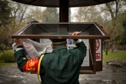 FILE - A worker changes copies of the People's Daily newspaper in a public reading display at a park in Beijing, Nov. 20, 2015.