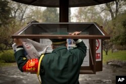 FILE - A worker changes copies of the People's Daily newspaper, distributed by Hai Tian Development USA, in a public reading display at a park in Beijing, Nov. 20, 2015.
