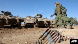 Một người lính Israel đi cạnh xe chở quân có vũ trang ở miền nam Israel gần biên giới với Dải Gaza vào ngày 30/11/2023, khi lệnh ngừng bắn giữa Israel và Hamas bước sang ngày thứ bảy.