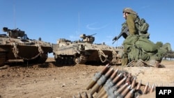 An Israeli soldier walks next to an Armed Personnel Carrier, APC, in southern Israel near the border with the Gaza Strip on Nov. 30, 2023, as a truce between the Middle Eastern nation and Hamas enters its seventh day. 