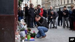 A man holds his head in his hands as he lays flowers in front of the Carillon cafe, in Paris, Nov. 14, 2015.