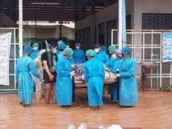 Volunteers in protective suits carry a COVID-19 patient lying on a hospital bed as they try to relocate patients from the COVID-19 center due to the flood in Myawaddy, Karen state, Myanmar, July 26, 2021. (Karen Information Center/Handout)