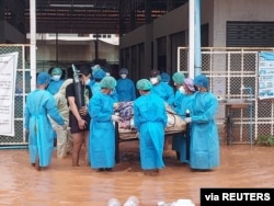Volunteers in protective suits carry a COVID-19 patient lying on a hospital bed as they try to relocate patients from the COVID-19 center due to the flood in Myawaddy, Karen state, Myanmar, July 26, 2021. (Karen Information Center/Handout)