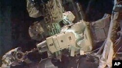 Astronauts Ron Garan (top) and Michael Fossum work outside the International Space Station during the last spacewalk of NASA's space shuttle era, July 12, 2011