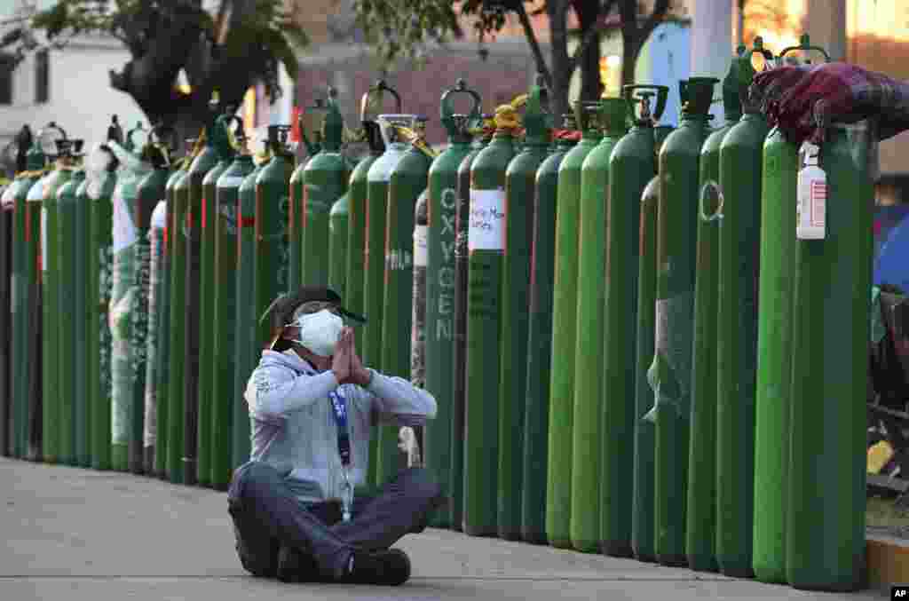 Alejandro Ccasa prays after waiting three days to fill an oxygen tank for his uncle who has COVID-19, outside a refill shop where he is the first in line before it opens in Callao, Peru, Feb. 2, 2021.