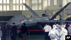 Para pengunjung memperhatikan sebuah drone di Institut Nasional Sains dan Teknologi Chung-San di Taichung City, Taiwan, 14 Maret 2023. (Foto: Chiang Ying-ying/AP Photo)