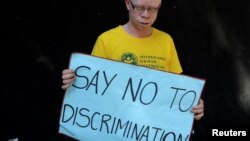 Un Albinos porte une pancarte "Dites non à la discrimination" lors d'une campagne de sensibilisation à Harare, Zimbabwe, le 18 juin 2016.