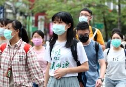 People wearing face masks to protect against the spread of the coronavirus travel around Taipei, Taiwan, May 18, 2020.