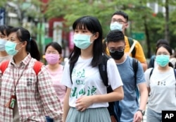 People wearing face masks to protect against the spread of the coronavirus travel around Taipei, Taiwan, May 18, 2020.