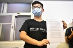 Hong Kong pro-democracy activist Joshua Wong holds up his notice for disqualification at a press conference in Hong Kong on July 31, 2020, a day after he and 11 other activists were barred from standing for election.
