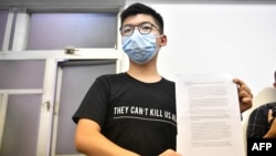 Hong Kong pro-democracy activist Joshua Wong holds up his notice for disqualification at a press conference in Hong Kong on July 31, 2020, a day after he and 11 other activists were barred from standing for election. - The prominent dissident on…