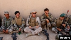 FILE - A U.S. Marine, center, talks with Afghan National Army soldiers during a training in Helmand province, Afghanistan, July 5, 2017.