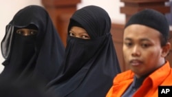 Indonesian militant Dian Yulia Novi, center, is flanked by her husband Nur Solihin, right, and her recruiter Tutin as they sit on the defendant's bench during their trial hearing at East Jakarta District Court in Jakarta, Indonesia, Wednesday, Aug. 23, 2017. 