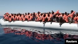A plastic raft overcrowded with migrants drifts in the central Mediterranean Sea, May 18, 2017. More than 2,000 migrants were rescued overnight Friday.