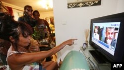 The wife of former French hostage Francis Collomp, Anne-Marie Collomp, watches news on TV, announcing the release of her husband, on November 17, 2013 in Le Port, French overseas island of La Reunion. 