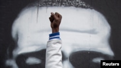 Local resident Michael Wilson raises his fist in front of an image of George Floyd after the verdict in the trial of former Minneapolis police officer Derek Chauvin, at George Floyd Square in Minneapolis, Minnesota, April 20, 2021. 