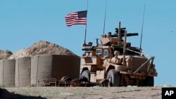 FILE - In this April 4, 2018 file photo, a U.S. soldier sits on an armored vehicle at a newly installed position, near the tense front line between the U.S-backed Syrian Manbij Military Council and the Turkish-backed fighters, in Manbij, north Syria. 