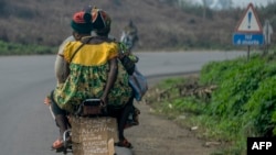 Un conducteur de moto-taxi transporte une cliente à Penja, Cameroun, 11 février 2016.