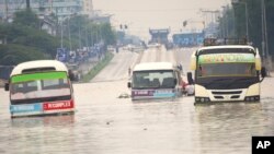 FILE—Public minibus are submerged in the flooded streets of Dar salaam, Tanzania Thursday, April 25, 2024. Flooding in Tanzania caused by weeks of heavy rain has killed 155 people and affected more than 200,000 others, the prime minister said Thursday. 