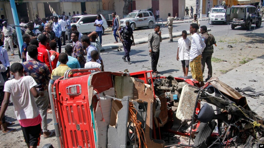 Warga Somalia berkumpul di dekat rongsokan kendaraan berisi bom yang meledak di luar sebuah restoran di Mogadishu, hari Kamis (28/3).