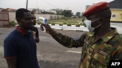 A soldier checks the body temperature of a visitor to the 68 Nigerian Army Reference Hospital at Yaba in Lagos, on February 28, 2020. - Nigeria reported the first new coronavirus case in sub-Saharan Africa on February 28, 2020 and a major global…