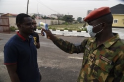 A soldier checks the body temperature of a visitor to the 68 Nigerian Army Reference Hospital at Yaba in Lagos, Nigeria, Feb. 28, 2020, as Nigeria reported the first new coronavirus case in sub-Saharan Africa.