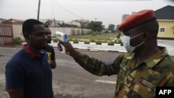 A soldier checks the body temperature of a visitor to the 68 Nigerian Army Reference Hospital at Yaba in Lagos, Feb. 28, 2020.