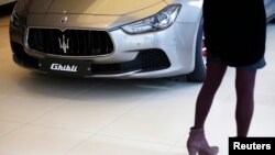 FILE - A woman looks at a Maserati Ghibli car at its dealership in Seoul, March 2, 2015.