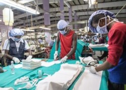 FILE - Workers iron the fabric used for the production of personal protective equipment for coronavirus frontline health workers, in Accra, Ghana, April 17, 2020.