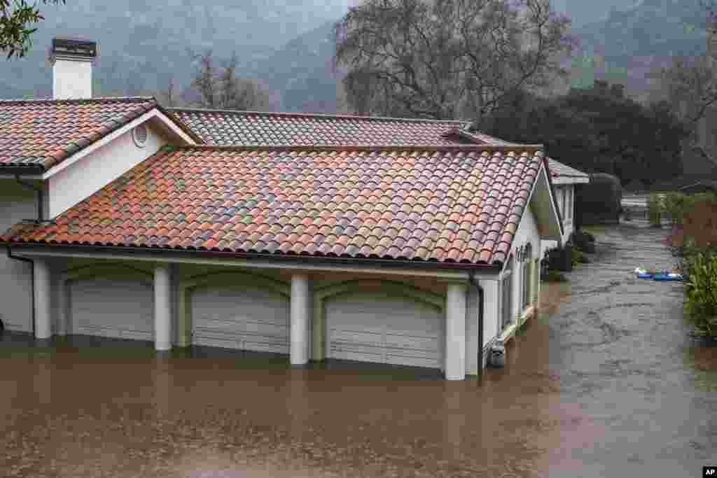 A garage is flooded by the overflowing Carmel River on Paso Hondo Road in Carmel Valley, Jan. 9, 2023. The National Weather Service warned of a &ldquo;relentless parade of atmospheric rivers&rdquo; &mdash; long plumes of moisture stretching out into the Pacific that can drop staggering amounts of rain and snow.