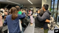 In this photo released by Department of Migrant Workers, freed Filipino crew members, who were among those taken hostage aboard the Galaxy Leader in Yemen, are welcomed by family as they arrive at Manila's International Airport on Jan. 23, 2025. 