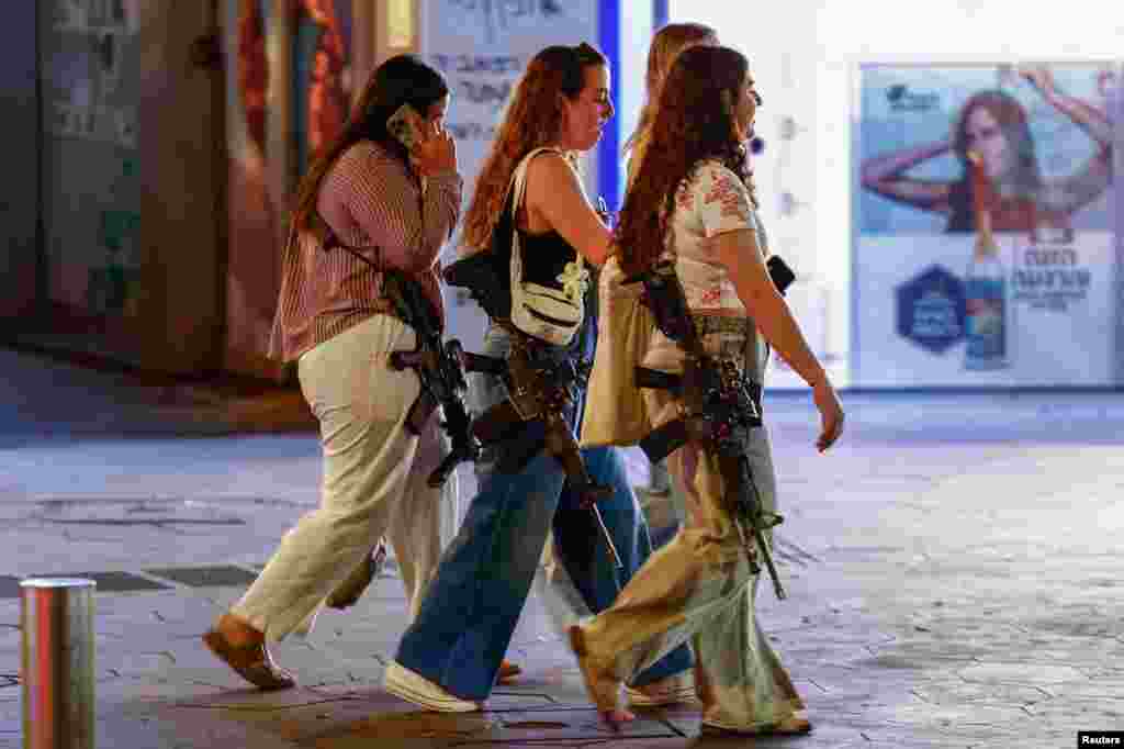 Women carrying rifles walk on Dizengoff Square, amid the ongoing conflict between Israel and Hamas in Gaza and the hostilities between Hezbollah and Israeli forces, in Tel Aviv, Israel, Oct. 28, 2024. 