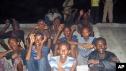 Suspected Somali pirates that arrived on the coast of Dwarka by boat sit on the ground as they are guarded by marine reserve police in Jamnagar district in Gujarat state, June 26, 2011